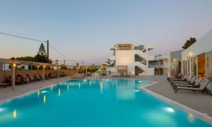 Basen i leżaki przy hotelu Marebello Beach Resort. Wieczorne światła odbijają się w wodzie.