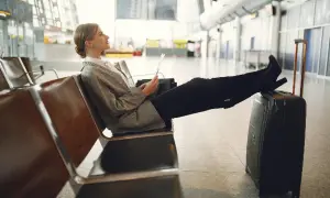 Kobieta z bagażem podręcznym czeka na lotnisku. Zastanawia się, ile wcześniej trzeba być na lotnisku z bagażem podręcznym.