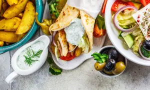 Pyszne dania kuchni greckiej: gyros, sałatka grecka, frytki i sos tzatziki.