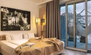 Przytulny pokój w hotelu dla dorosłych z dużym łóżkiem, abstrakcyjnym obrazem i widokiem na jezioro.