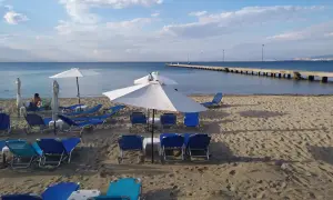 Puste saloniki plażowe czekają na gości. W oddali widać długie molo i błękitne morze.