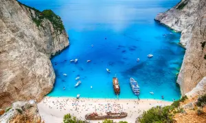 Zatoka Navagio, jedna z największych wysp greckich, z turkusową wodą, plażą pełną ludzi i wrakiem statku.