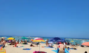 Słoneczne **bari plaże** tętnią życiem. Ludzie opalają się pod kolorowymi parasolami, kąpią w morzu i odpoczywają na piasku.