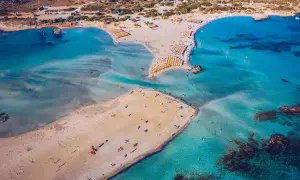 Rajska, piaszczysta kreta plaża Elafonisi z turkusową wodą i licznymi parasolami.