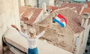 Kobieta z chorwacką flagą na tle dachów. W tle widać piękne, stare miasto.