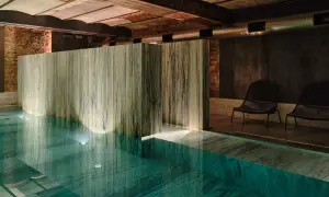 Wnętrze basenu w jednym z najlepszych hoteli spa. Marmurowe wykończenia, dyskretne oświetlenie i dwa fotele tworzą atmosferę relaksu.