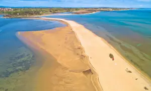 Chorwacja plaże piaszczyste, piaszczysta mierzeja otoczona turkusową wodą, w oddali widać zabudowania.