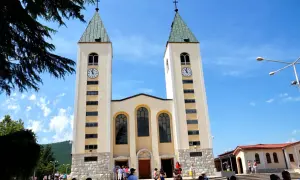 Kościół w Medziugorie, miejsce znane z objawień maryjnych. Tłumy pielgrzymów podziwiają architekturę.