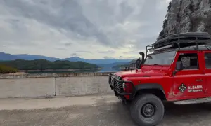 Czerwony Land Rover na tle gór i jeziora w Albanii. Listopad, pogoda pochmurna, idealna na off-road.