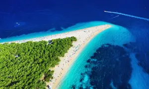 Widok z lotu ptaka na słynne chorwackie plaże Zlatni Rat. Turkusowe morze, biały piasek i zielony las tworzą rajski krajobraz.