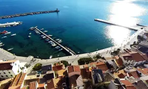 Widok na port i miasteczko Baška w Chorwacji. Woda jest turkusowa, a na nabrzeżu cumują łodzie.