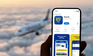 Aplikacja Ryanair na telefonie, z samolotem w tle. Sprawdź, co to za aplikacja do tanich lotów.