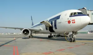 Samolot LOT-u na płycie lotniska, gotowy do startu. Zastanawiasz się, jak zbierać mile lotnicze? Podróżuj tymi liniami!