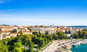 Piękna pogoda w Puli, Istrii. Widok na amfiteatr, port z łodziami i urokliwe miasto pod błękitnym niebem.