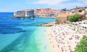 Słoneczna plaża w Dubrowniku, idealna na chorwacja last minute all inclusive. Turkusowe morze, zabytkowe mury i mnóstwo wypoczywających.
