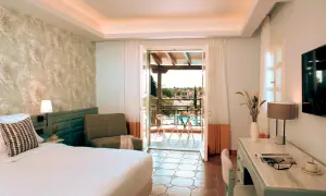 Pokój w Eretria Hotel & Spa Resort z widokiem na basen i morze. Wygodne łóżko, fotel i balkon zapraszają do relaksu.