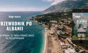 Piękna linia brzegowa Albanii, z widokiem na miasto i góry. Na ekranie telefonu przewodnik po Albanii, idealny na podróż.