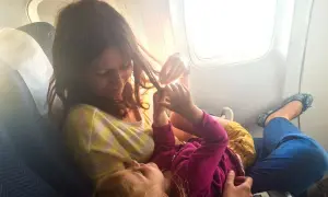 Mama bawi się włosami dziecka w samolocie. Dzieci w samolocie, podróżują z uśmiechem.