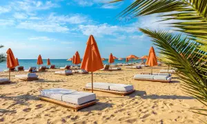 Słoneczny dzień na plaży w Złotych Piaskach. Pomarańczowe parasole i leżaki czekają na gości.
