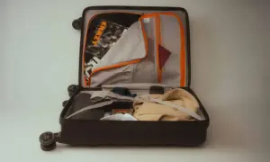 Otwarta walizka z ubraniami, paszportem i kosmetykami. Idealny przykład, jak spakować się do samolotu, by niczego nie zapomnieć.