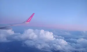Skrzydło samolotu rejsowego Wizz Air nad chmurami o zachodzie słońca.