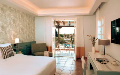 Pokój w Eretria Hotel & Spa Resort z widokiem na basen i morze. Wygodne łóżko, fotel i balkon zapraszają do relaksu.