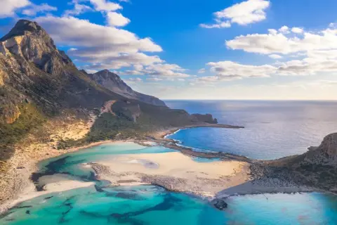 Malownicze widoki na Balos Lagoon z turkusową wodą, piaszczystymi plażami i skalistymi górami pod błękitnym niebem.