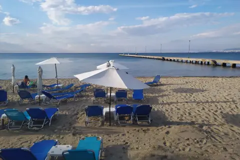 Puste saloniki plażowe czekają na gości. W oddali widać długie molo i błękitne morze.