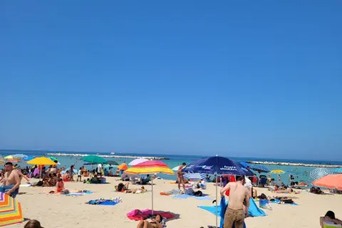 Słoneczne **bari plaże** tętnią życiem. Ludzie opalają się pod kolorowymi parasolami, kąpią w morzu i odpoczywają na piasku.