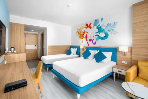 Pokój hotelowy z dwoma łóżkami i kolorową grafiką na ścianie. To jak **club sun heaven** dla podróżnych.