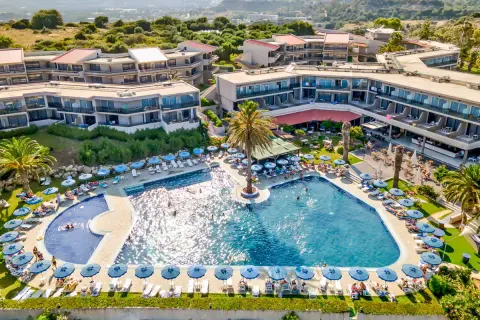 Relaks przy basenie w Cathrin Hotel Rodos. Goście odpoczywają na leżakach pod parasolami, niektórzy pływają w turkusowej wodzie.