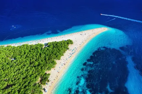 Widok z lotu ptaka na słynne chorwackie plaże Zlatni Rat. Turkusowe morze, biały piasek i zielony las tworzą rajski krajobraz.