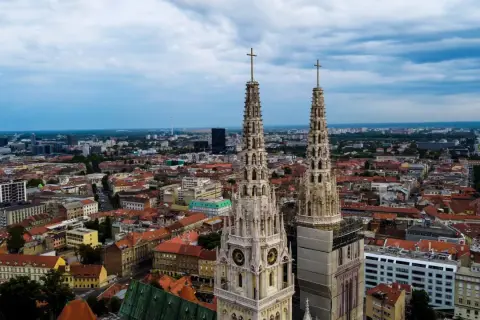 Dwie wieże katedry górują nad miastem. W oddali widać nowoczesne budynki i zielone tereny. To wspaniałe zagrzeb atrakcje.