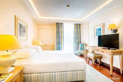 Pokój w Pestana Royal Premium All Inclusive Ocean & Spa. Dwa łóżka, stolik z telewizorem, krzesło i zasłony w niebiesko-żółte wzory.