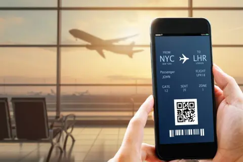 Bilet lotniczy na telefonie: NYC do LHR, pasażer John, lot LP418. IATA co to? To kod lotniska.