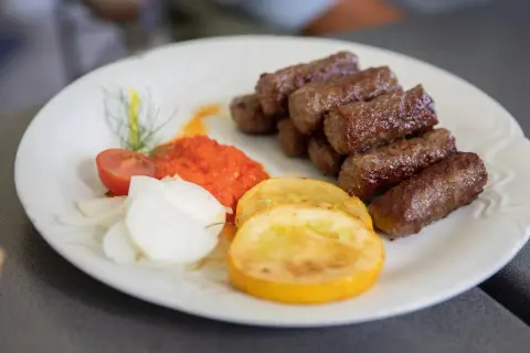 Cevapi, klasyka kuchni słoweńskiej, podane z ajwarem, cebulą i pomidorem.