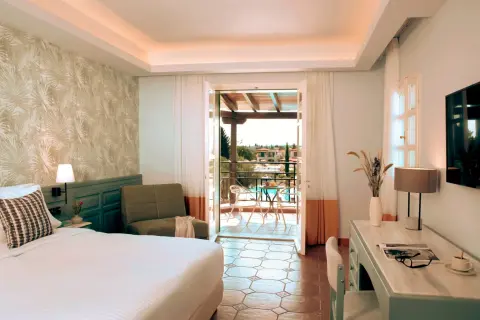 Pokój w Eretria Hotel & Spa Resort z widokiem na basen i morze. Wygodne łóżko, fotel i balkon zapraszają do relaksu.