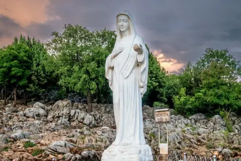 Biały posąg Matki Bożej na skalistym wzgórzu, miejsce pielgrzymek do Medjugorie.