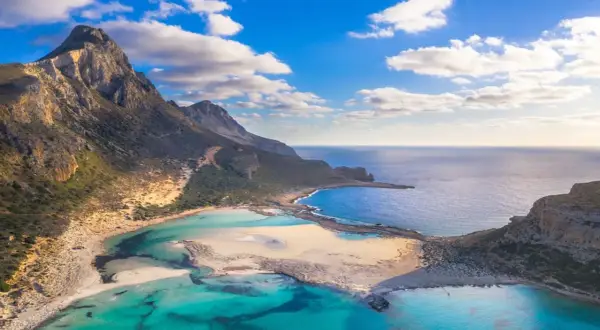 Malownicze widoki na Balos Lagoon z turkusową wodą, piaszczystymi plażami i skalistymi górami pod błękitnym niebem.