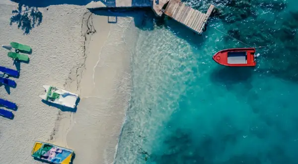Widok z lotu ptaka na plażę w Albanii z łodziami i turkusową wodą.