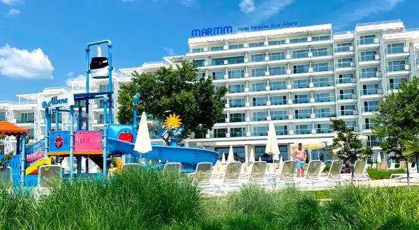 Kolorowy aquapark i hotel Maritim Paradise Blue Albena w Bułgarii, z leżakami i zieloną trawą.
