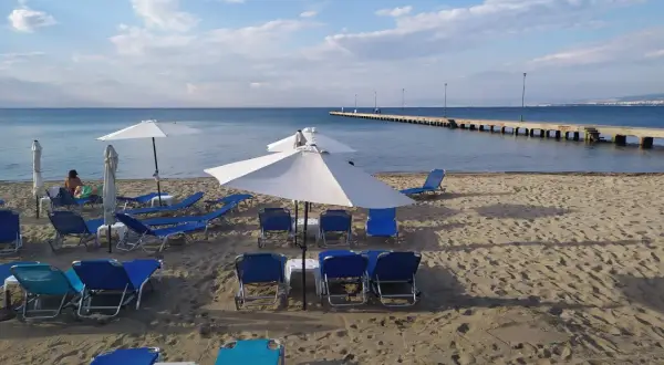 Puste saloniki plażowe czekają na gości. W oddali widać długie molo i błękitne morze.