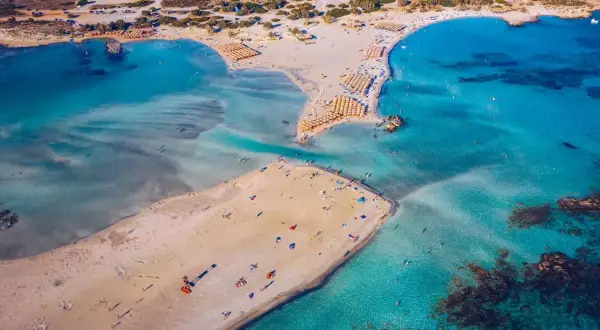 Rajska, piaszczysta kreta plaża Elafonisi z turkusową wodą i licznymi parasolami.