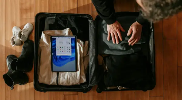 Pakowanie bagażu podręcznego: ubrania, buty i tablet z aplikacją do sprawdzania wymiarów bagażu.