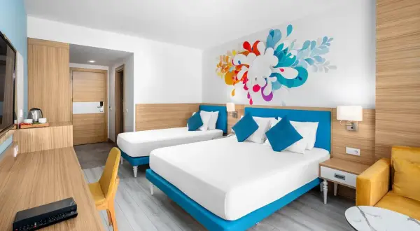 Pokój hotelowy z dwoma łóżkami i kolorową grafiką na ścianie. To jak **club sun heaven** dla podróżnych.