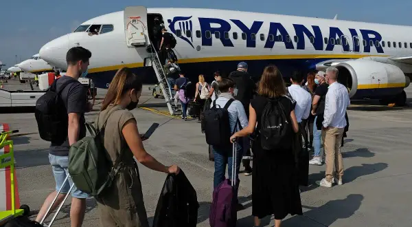 Kolejka do samolotu Ryanair. Pasażerowie z bagażami czekają na boarding ile przed odlotem.