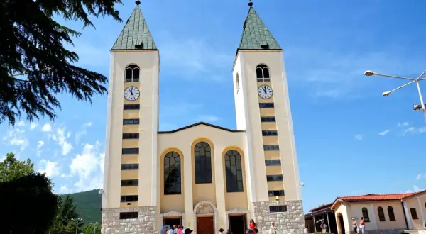 Kościół w Medziugorie, miejsce znane z objawień maryjnych. Tłumy pielgrzymów podziwiają architekturę.