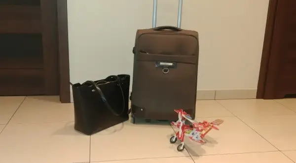 Walizka, torebka i model samolotu czekają na lot samolotem w ciąży w 1 trymestrze.