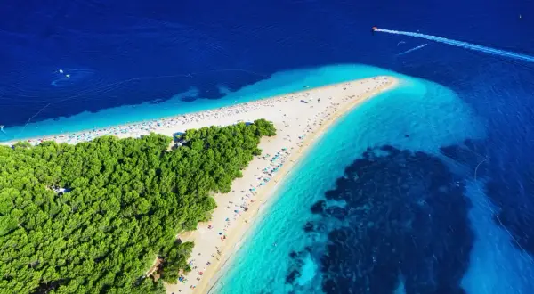 Widok z lotu ptaka na słynne chorwackie plaże Zlatni Rat. Turkusowe morze, biały piasek i zielony las tworzą rajski krajobraz.