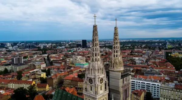 Dwie wieże katedry górują nad miastem. W oddali widać nowoczesne budynki i zielone tereny. To wspaniałe zagrzeb atrakcje.